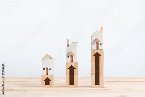 Fototapeta Miniature white house on wooden block with growth arrow sign in property investment concept