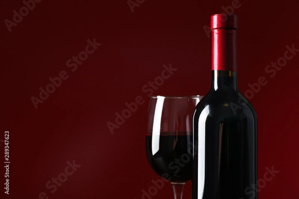 Fototapeta Bottle and glass with wine against red background, copy space