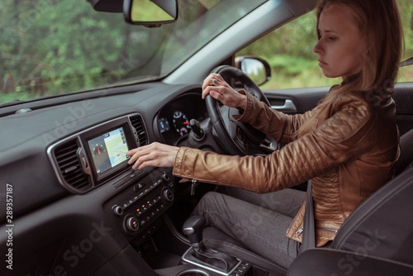 Fototapeta woman in car, checks navigation map on touch screen in car. Lost in finding a route, choosing a route in parking lot, choosing a navigation map, final route. Online application on Internet.