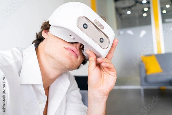 Obraz Man wearing virtual reality goggles in modern bright co-working office. the VR experience.