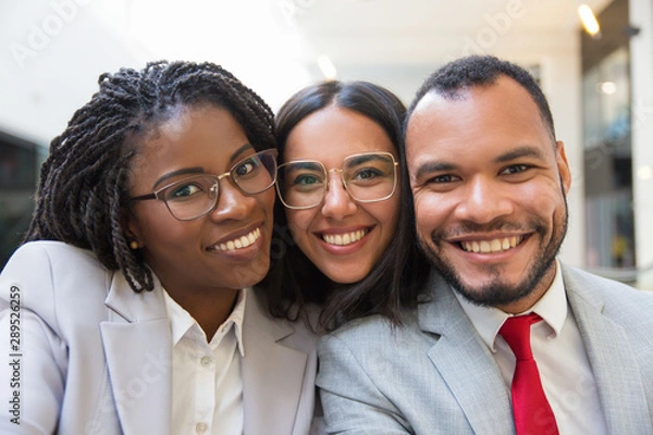 Fototapeta Multiethnic business colleagues smiling at camera. Portrait of happy young business people smiling at camera together. Cooperation concept