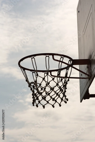 Obraz Closeup of a basketball hoop, basket with white net and blue sky with clouds in background