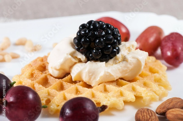 Fototapeta Sweet waffles with sour cream and fruit on a light background.
