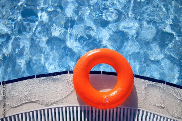 Fototapeta floating orange ring on edge of swimpool with waves reflecting i