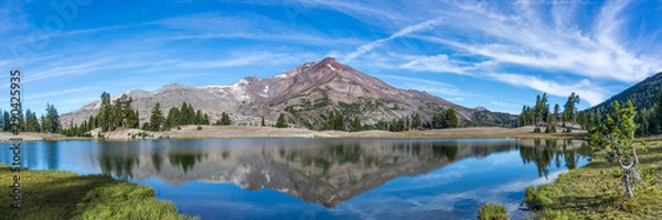 Obraz Volcanic mountain in morning light reflected in calm waters of lake.	