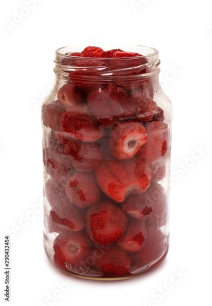Fototapeta Red strawberry berries in a glass jar isolated on white background.