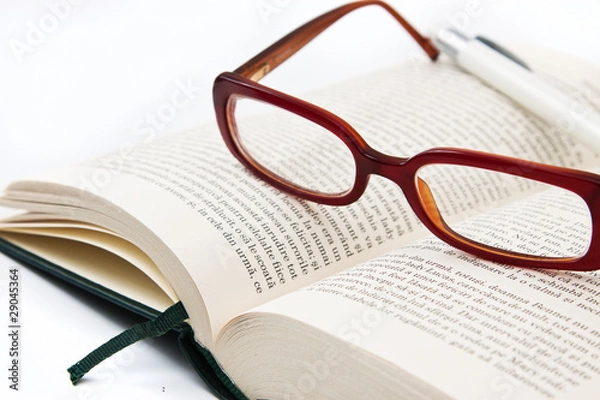 Fototapeta Glasses on book and pen isolated in white