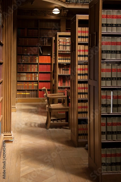 Fototapeta Wood style nice library with chair and full of book on shelf. Place for student to study and read.