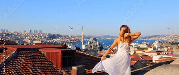 Obraz Happy young woman standing on the rooftop in Istanbul Turkey. Back view of the girl in white long dress at the famous tourist attraction of Istanbul. Travel, tourism, excursions.