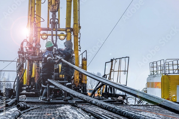 Obraz Offshore oil rig worker prepare tool and equipment for perforation oil and gas well at wellhead platform. Making up a drill pipe connection. A view for drill pipe connection from between the stands