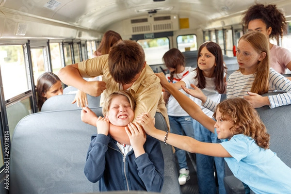 Fototapeta Classmates going to school by bus boy strangling kid angry while others trying to stop him