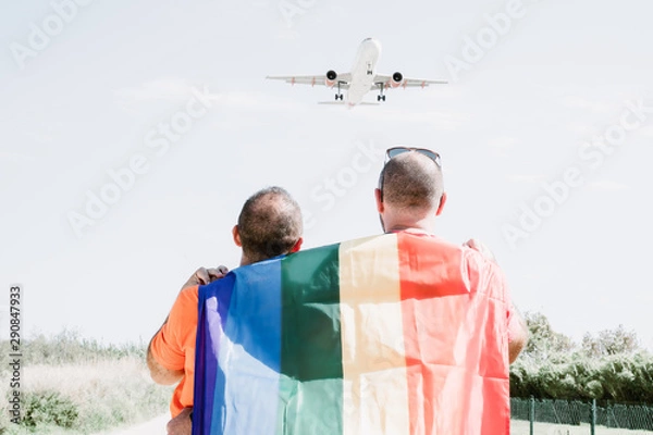 Obraz Two gay men look at a plane flying in the sky.LGTB,LGBT
