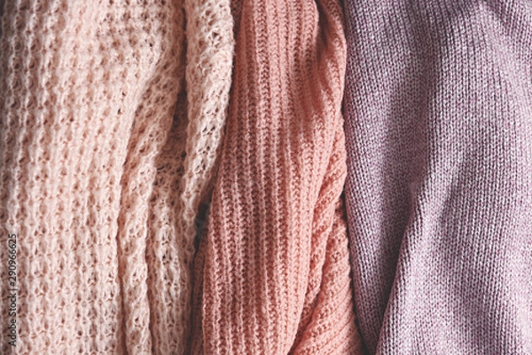 Fototapeta Bunch of knitted warm pastel color sweaters with different vertical knitting patterns hanging in bunch, clearly visible texture. Stylish fall / winter season knitwear clothing. Close up, copy space.
