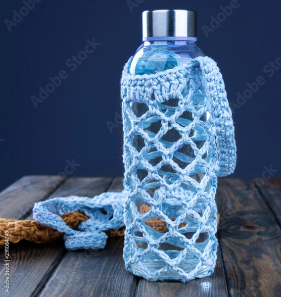 Fototapeta Close-up of a water bottle in a blue case on a wooden table