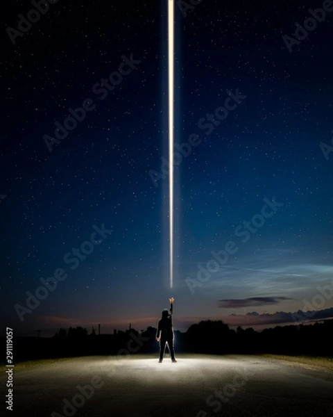 Fototapeta Man standing in the middle of the road with the light beam from his hand