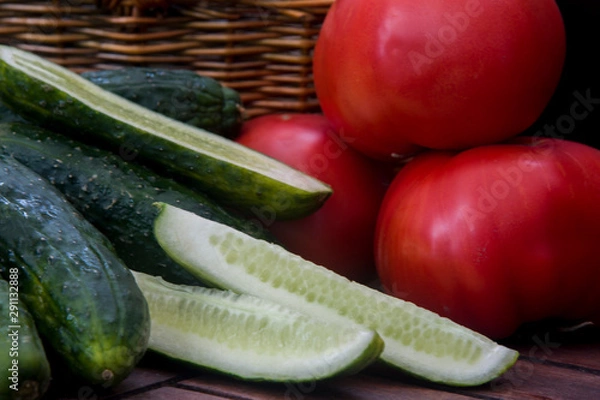 Fototapeta tomatoes and cucumbers next to a wicker basket