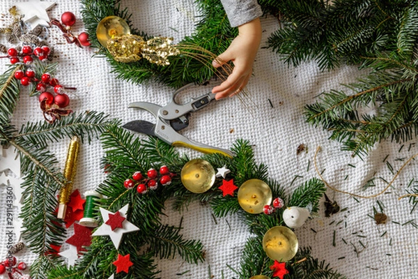 Fototapeta Hands of a child decorate Christmas Advent wreath from fir twigs