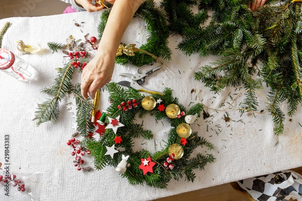Fototapeta Hands of a woman make Christmas Advent wreath from fir twigs