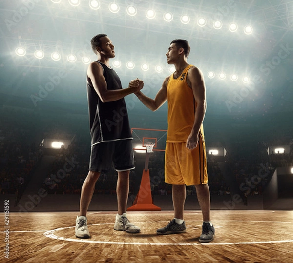 Obraz Two professional basketball players on a basketball court shaking hands before the game