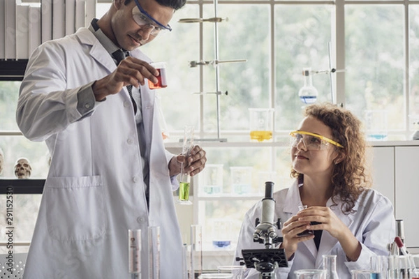 Fototapeta Team of Medical Research Scientist Conducts Experiments in Laboratory with Microscope, Test Tubes, Micropipette and other equipment.