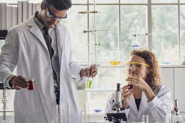 Fototapeta Team of Medical Research Scientist Conducts Experiments in Laboratory with Microscope, Test Tubes, Micropipette and other equipment.
