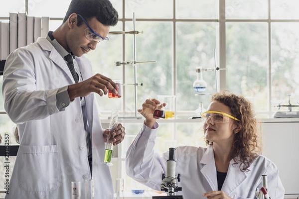 Fototapeta Team of Medical Research Scientist Conducts Experiments in Laboratory with Microscope, Test Tubes, Micropipette and other equipment.