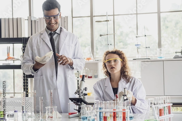 Fototapeta Team of Medical Research Scientist Conducts Experiments in Laboratory with Microscope, Test Tubes, Micropipette and other equipment.