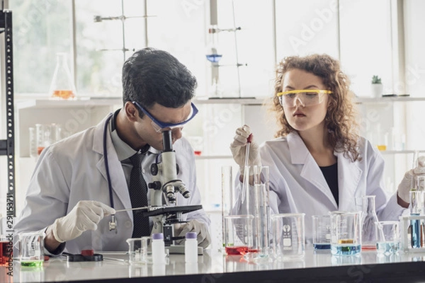 Fototapeta Team of Medical Research Scientist Conducts Experiments in Laboratory with Microscope, Test Tubes, Micropipette and other equipment.