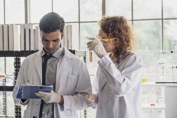 Fototapeta Team of Medical Research Scientist Conducts Experiments in Laboratory with Microscope, Test Tubes, Micropipette and other equipment.