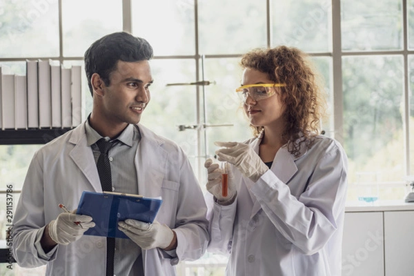 Fototapeta Team of Medical Research Scientist Conducts Experiments in Laboratory with Microscope, Test Tubes, Micropipette and other equipment.