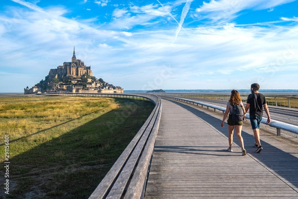 Fototapeta A couple heads to Mont Saint Michael on the only access road. On foot it is one of the options allowed for access, perhaps the most beautiful because it is enjoying a spectacular landscape.