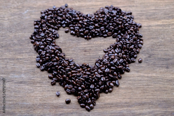 Fototapeta coffee beans in shape of heart on wooden table