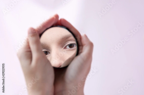 Fototapeta Hands holding a mirror with a reflection of the girl's eyes