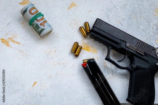 Fototapeta 9 mm pistol gun bullets strewn and roll american dollar banknotes on rustic oak table.