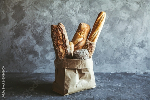 Fototapeta French pastries, baguettes on a gray background in a paper bag.