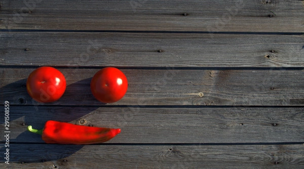 Obraz Smile with hot red pepper with two tomatoes on a dark wooden background
