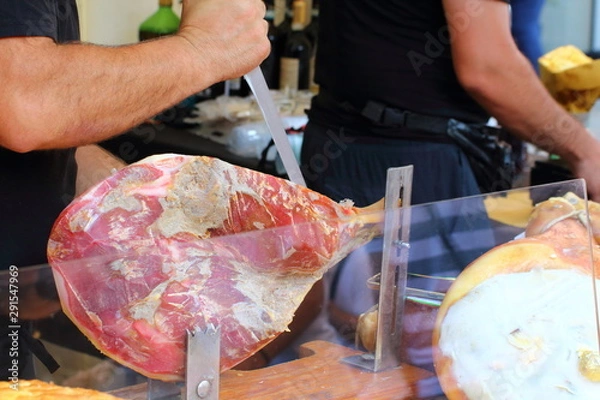 Fototapeta cook cuts some slices of seasoned ham with the meat knife