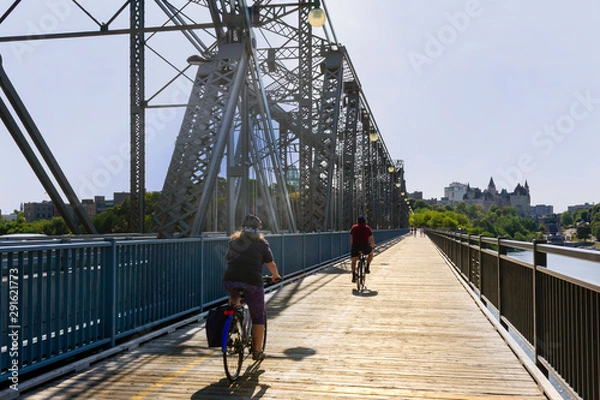 Obraz bridge open to walking and cycling pedestrian friendly wooden vintage bridge in Ottawa and two cyclists