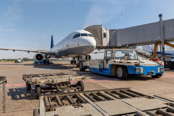 Obraz Pushback car is ready to tow a passenger plane, which stands near the telescope gate. Airport life and travel concept