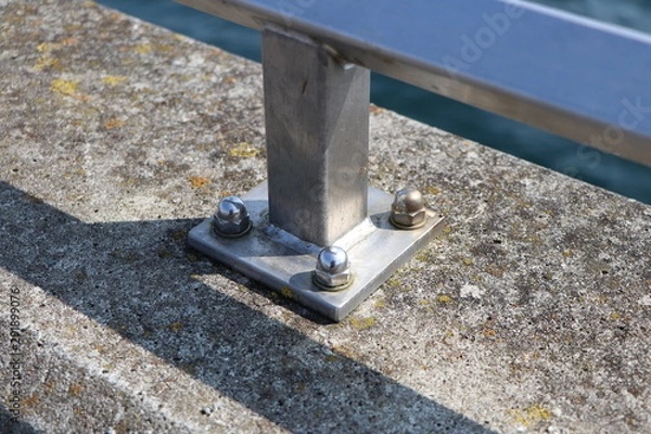 Obraz Closeup of a metal railing screwed tightly on concrete at a harbour pier