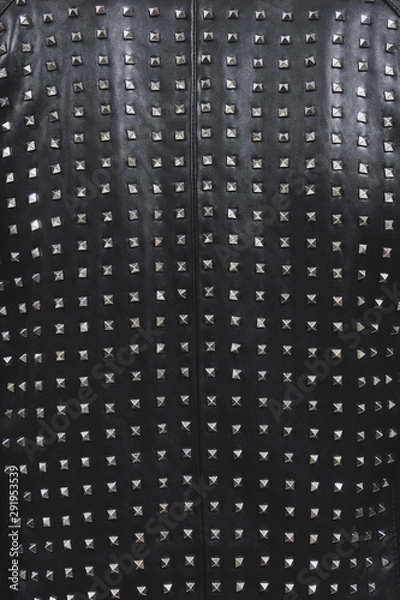 Fototapeta Back of a black leather jacket with metal rivets. Biker or punk studded style. Sample of stylish clothing products. Textured background. Fashionable rocker clothes. Vertical photo.