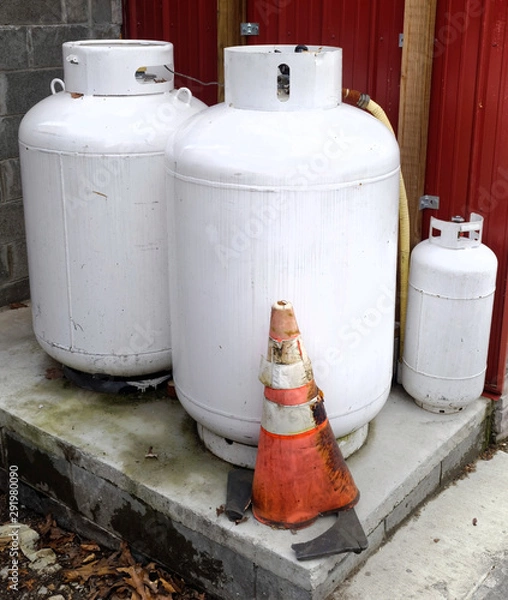 Obraz Three white propane gas tanks on concrete base.