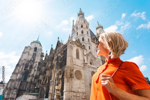 Obraz A young woman in a bright orange dress stands on the background of St. Stephen's Cathedral in Vienna, Austria