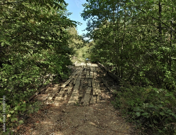 Obraz old wooden bridge over a mountain stream on a forest road