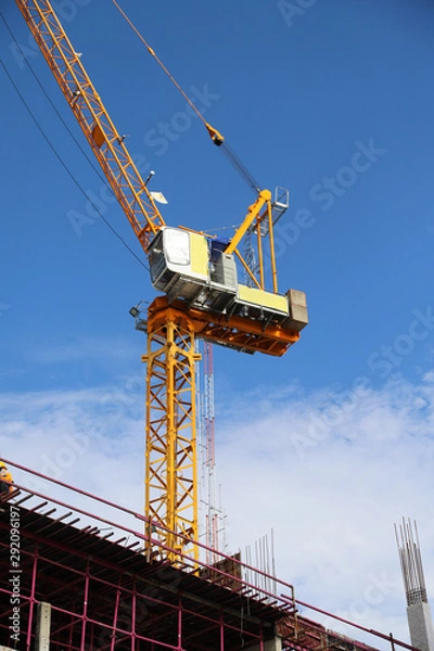 Fototapeta Closeup of construction crane under working at construction site with blue sky background. 