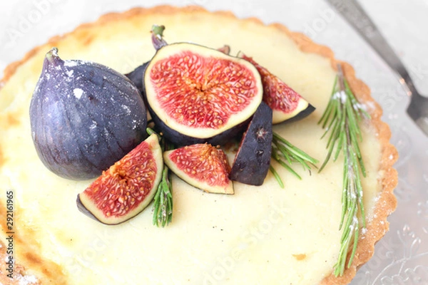 Fototapeta gorgeous round french classic homemade shortcake pastry dough vanilla custard tart cake decorated with figs and rosemary on glass stand near with retro fork on grey table cloth. Insta food photo style