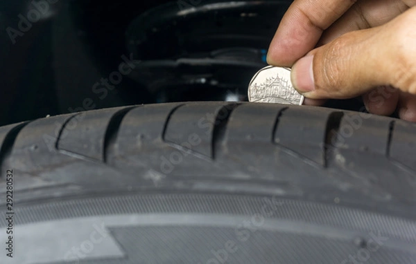 Fototapeta Man place a penny into tread grooves across the tire for checking tire tread depth and wear, Tire Tread and the Penny Test,Measuring Tread Depth With the Penny Test