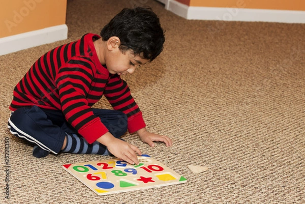 Fototapeta Preschooler Working On Numbers and Shapes Puzzle