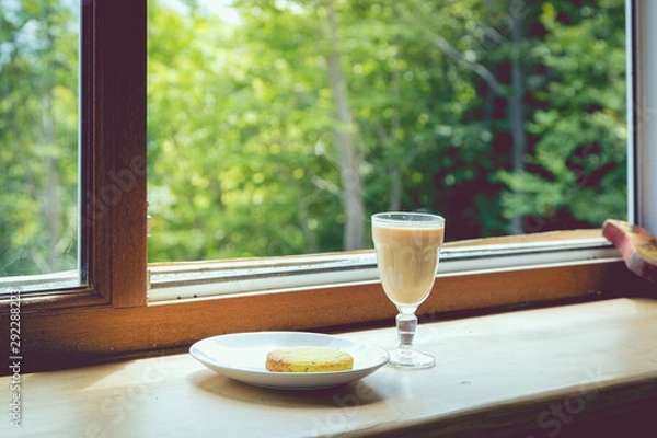 Fototapeta Tea with milk and spices on the background of an open window with mountain views