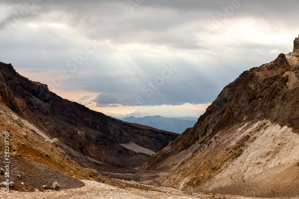 Fototapeta Sunset in the mountains, the rays of the sun breaking through the clouds. Mutnovsky Volcano, Kamchatka Peninsula, Russia